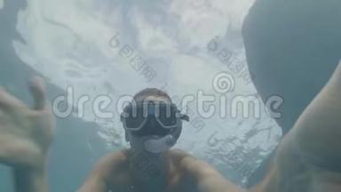 男子浮潜在面具和管游泳野生鲸鲨在清澈的海水和拍摄自拍视频。 男子
