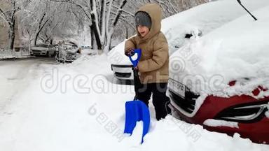 4k镜头快乐微笑的幼儿男孩用大雪铲在停车场上挖雪堆