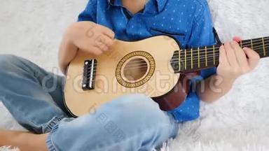 一个孩子把小吉他弹得很近。 弹吉他，唱歌，音乐，教育，节奏。