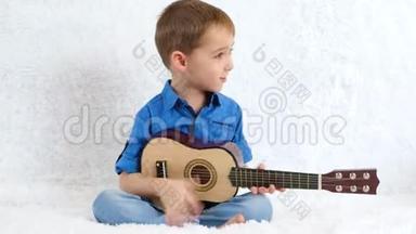 那个淘气的男孩坐在沙发上弹吉他。那<strong>孩子唱歌</strong>。音乐，教育，声乐。