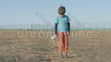 孤儿。 在难民营地区被遗弃的孤独儿童。 穿着脏衣服的男孩拿着玩具毛绒兔子无家可归的小东西