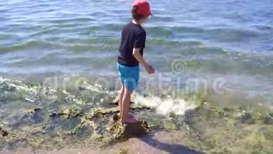 快乐的孩子正在石海上平衡。 暑假，健康的生活方式