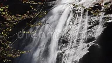 瀑布。 水流向下流过悬崖和岩石，靠近。 瀑布附近的小溪里泼水。 透明水晶和灰色
