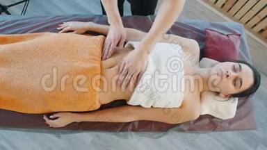 一个按摩师为一个年轻的女人准备用<strong>抚摸</strong>的动作来放松胃按摩
