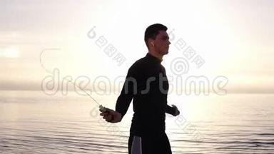 <strong>高个子</strong>、肌肉发达的年轻人在海边用跳绳锻炼。 从事户外运动的年轻人