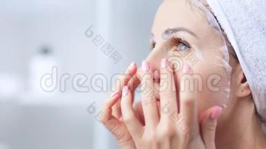 美丽的年轻女子将白色纺织面膜敷于面部肌肤，清洁毛孔