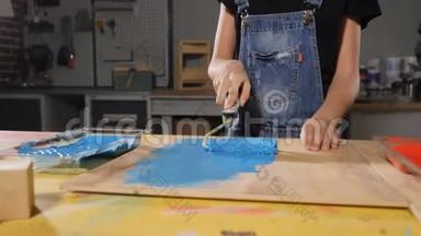 一个画蓝色的小女孩的特写镜头。 用滚筒画板。 快关门。 慢动作。 高清高清