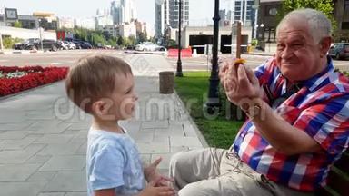 4k视频：<strong>老爷爷</strong>在公园的长椅上玩玩具和他蹒跚学步的孙子