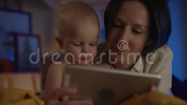妈妈给躺在床上的可爱宝宝看书，给他看不同的照片，给他看流动相机