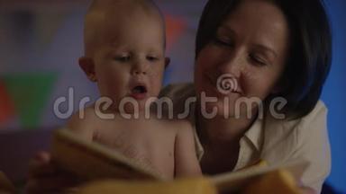 可爱的宝宝和妈妈一起坐在床上为他读童话