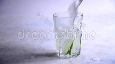 加冰的水和切成片的石灰倒进玻璃杯。慢动作。清爽夏日饮料