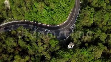 高空俯视图：汽车在曲折蜿蜒的道路上行驶，穿过山坡上茂密的云杉林。