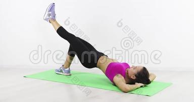 一个年轻的黑发女人躺在一个健身室的伴侣身<strong>上</strong>，<strong>拿起</strong>石头。