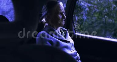 一位满脸皱纹的老妇人晚上坐在车里