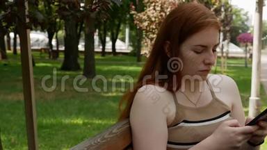 公园里的女孩在社交网络上交流，阳光明媚的长凳上