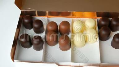 一个半空的盒子，里面有白巧克力、黑巧克力和牛奶巧克力做成的糖果状的松饼甜点