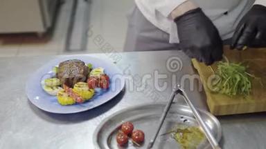 餐厅厨师的双手，装饰着美味的牛排、玉米、柠檬草、番茄樱桃和铃铛片