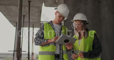 专业工程师穿着<strong>安全背心</strong>和头盔工作与数字平板和蓝图。