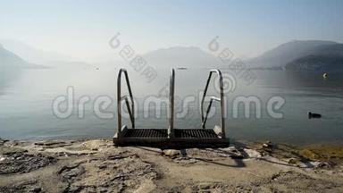 清晨，法国阿尔卑斯山`安纳西湖的海滩上有一个水池栏杆，背景是雾和是雾和山
