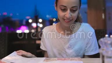 年轻的美女在餐厅看菜单，<strong>翻页</strong>，选择餐盘，午餐约会