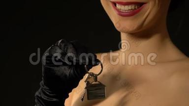 一位微笑的女士把钥匙和房子的钥匙链对着镜头，房地产市场
