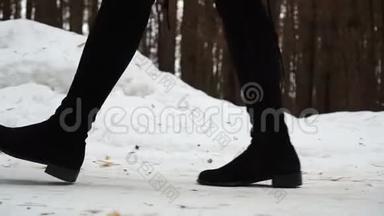 女人穿着靴子`雪漠上行走的特写镜头。