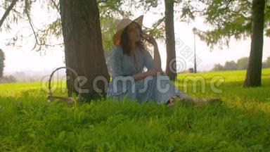 诗意的美丽女孩坐在松树附近的公园里