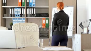 办公室里的红发女商人检查了<strong>后面</strong>的文件夹，然后来到办公桌前