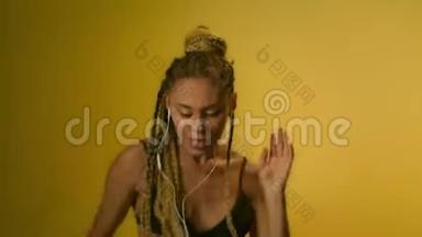 非洲女孩在黄墙手机上听音乐。 非洲女孩跳舞