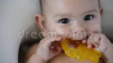 可爱的婴儿带着黄色的牙齿环。 可爱的婴儿肖像