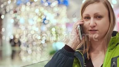 女人在智能手机上说话，尴尬而害羞。 4.她正站在<strong>商场</strong>的一个灯泡下