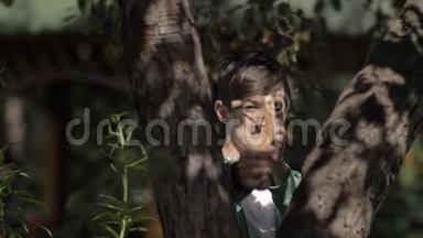 男孩躲在一棵树后面，瞄准一个在户外玩<strong>弹弓</strong>的人