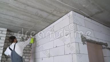 建筑工人用喷水器<strong>湿润</strong>墙壁，以便进一步处理