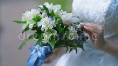 新娘手里拿着一大束漂亮的结婚花束，抚摸着花束里的花，用手指抚摸着