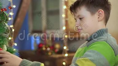 一个穿毛衣的男孩在家中的圣诞树附近检查它。 在圣诞灯的背景下