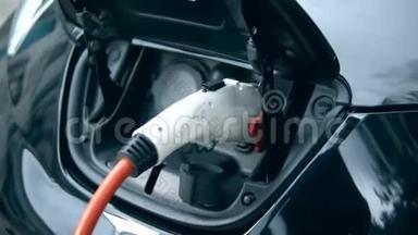 一个人把充电电缆插在他的电动汽车上。 创新电动混合动力汽车充电..