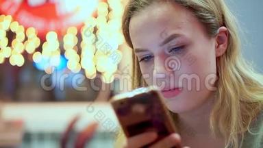 少女看着智能手机留言，眉头紧锁.. 她正在咖啡馆里吃晚饭。 快餐，晚上，在