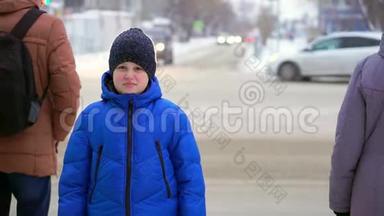 穿着<strong>蓝色羽绒服</strong>的少年站在街上。 汽车在后台，男孩在看。