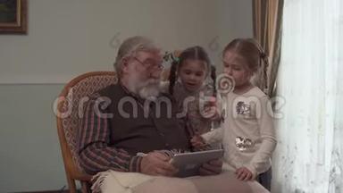 大胡子老人坐在<strong>摇椅</strong>上，手里拿着平板电脑。 两个小女孩站在爷爷旁边看着