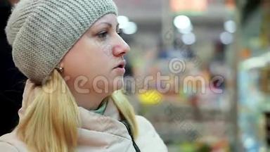 一个穿着冬天衣服的女人在超市里读一罐食物上的<strong>课文</strong>。 她把罐子放在架子上