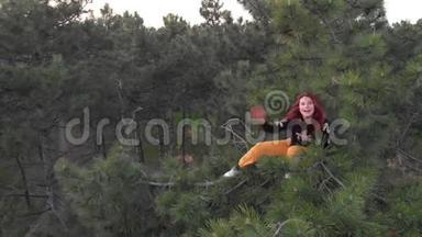 活泼活泼开朗的红发女青年爬上松树顶。空投针叶林