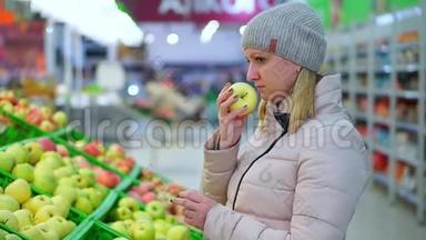穿冬天衣服的女人在超市摘水果。 她看起来像苹果。
