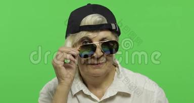 一位戴着太阳镜和帽子的老妇人微笑着。 <strong>老奶奶</strong>。 铬键