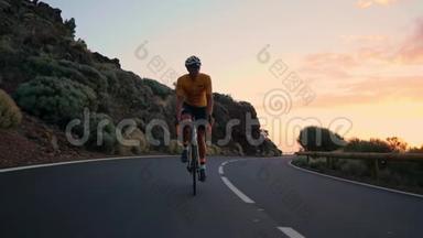 一个年轻的运动员骑着自行车骑在山蛇上，戴着黄色的t恤头盔和运动装备，看着。
