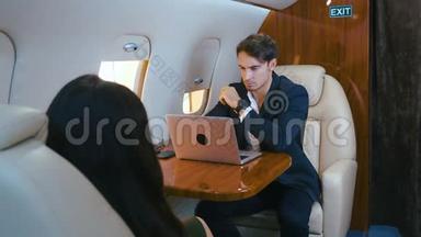 年轻的商人在私人飞机上用笔记本电脑工作。 成功的商业百万人头等舱旅行