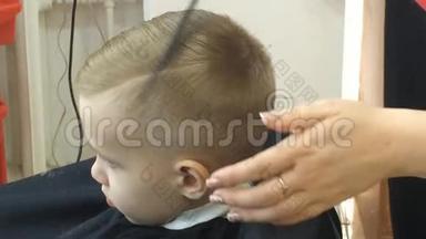 特写小男孩发型。 孩子的发型。 在儿童美发沙龙烘干头发.. 定型吹风机.. 儿童理发