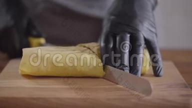 厨师的双手戴着黑色<strong>厨房手套</strong>，制作沙瓦玛特写。 厨师的切割把沙尔玛卷成两块然后