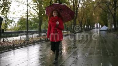 穿红衣服的女足在<strong>雨中撑伞</strong>行走。 红发女人穿着带伞的红色外套