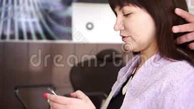 年轻的黑发女人手里拿着电话坐在美容院