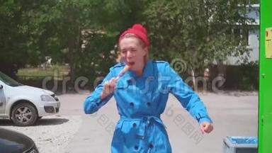 有趣的女孩在夏天吃冰淇淋。 金发女郎很有趣，穿着一件蓝色的外套，夏天戴着一顶红色的帽子。 幽默。
